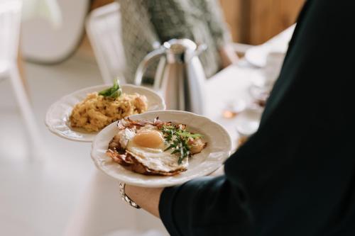 a person holding a plate of food on a table at Haus Alpenrose in Egg
