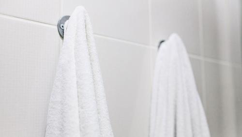 a white towel hanging on a door in a bathroom at Magnuson Hotel Sand Springs – Tulsa West in Sand Springs