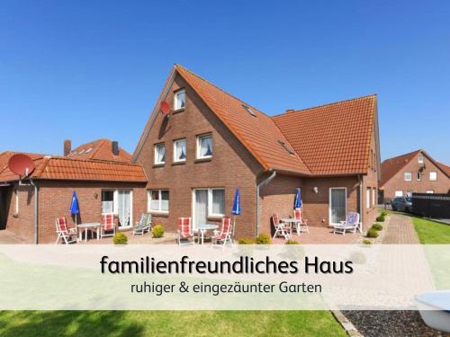 a house with a yard with tables and chairs at strandnahe Familien-Oase mit Kinderbuggy in Bensersiel