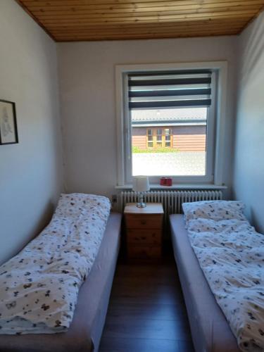 Duas camas num pequeno quarto com uma janela em Apartment in Hirtshals em Hirtshals