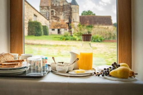 un tavolo con un piatto di cibo e una bottiglia di succo d'arancia di La Queurie a La Courbe
