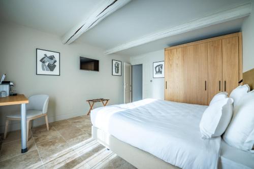 1 dormitorio con 1 cama blanca grande y escritorio en Hotel La Bastide d'Eygalières, en Eygalières