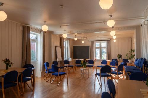a conference room with tables and chairs and a screen at Fokhol Gård Gjestehus in Stange