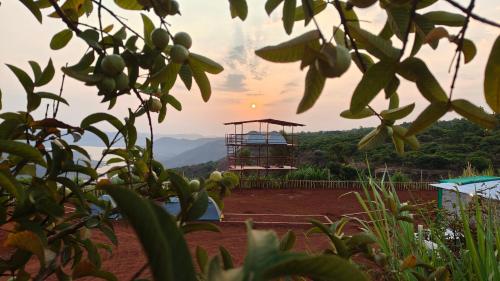 a view of the sunset from a hill with a tower at Yuva Yatri Campsite in Mahabaleshwar