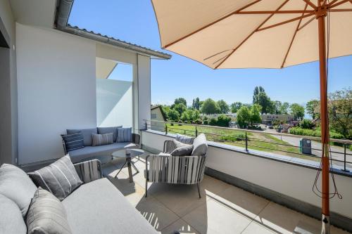 a balcony with a couch and an umbrella at Hotel Heinzler am See in Immenstaad am Bodensee
