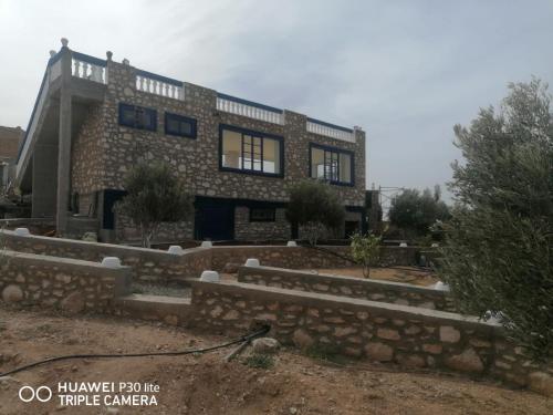a large brick house with a stone wall at Maison Ayachi in El Aadamna