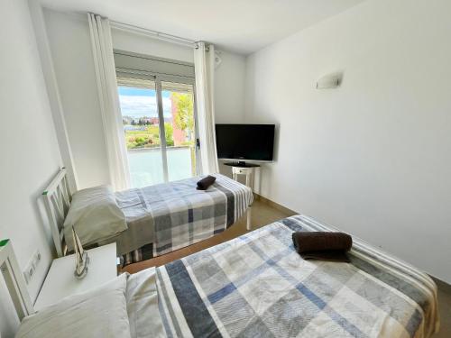 Habitación con 2 camas, TV y ventana. en NEW! Apartamento con 2 piscinas, parque infantil, a 1 min de la playa, en Sant Antoni de Calonge