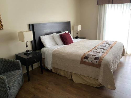 a bedroom with a large bed and a chair at Excelsior Hôtel Spa Sainte-Adèle in Sainte-Adèle