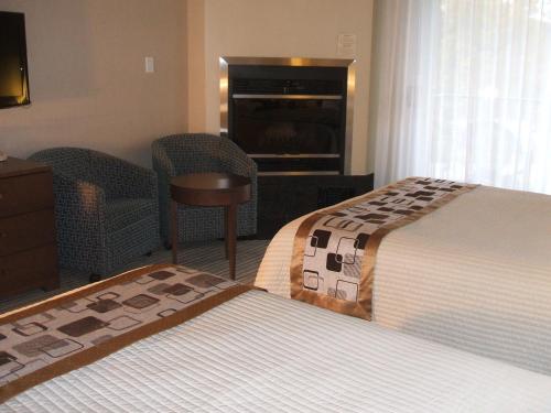 a hotel room with two beds and a fireplace at Excelsior Hôtel Spa Sainte-Adèle in Sainte-Adèle