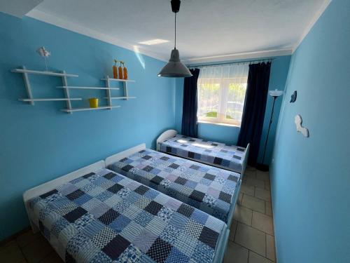 a bedroom with a bed with blue walls and a window at Apartament Nostalgia in Gąski