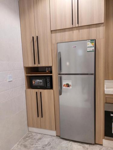a kitchen with a stainless steel refrigerator and wooden cabinets at Elite House in Taif