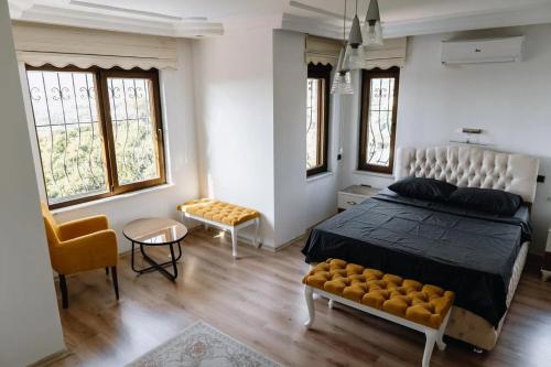 a bedroom with a bed and a chair and windows at Yıldız Villa in Alanya