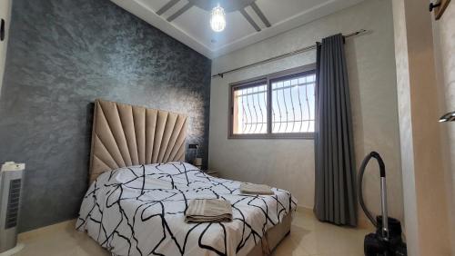 Schlafzimmer mit einem Bett und einem Fenster in der Unterkunft Bel appartement dans une résidence calme in Meknès