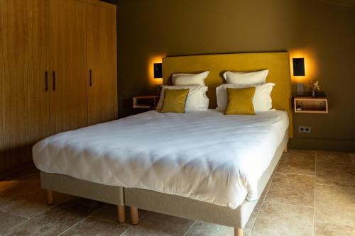 a bedroom with a large bed with white sheets and yellow pillows at Hotel La Bastide d'Eygalières in Eygalières