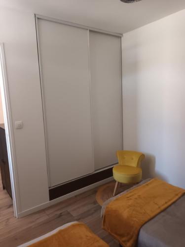 a bedroom with a bed and a yellow chair at Le Samui in Saint-Hilaire-sur-Yerre