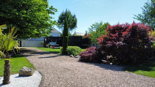 uma entrada de cascalho num jardim com árvores e arbustos em Villa Louméa - Le Loft avec jacuzzi em Friesenheim