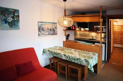 une cuisine avec une table et un canapé rouge dans l'établissement Résidence Le Cairn - APPARTEMENT N° 407 LE CAIRN MAE-6331, aux Orres