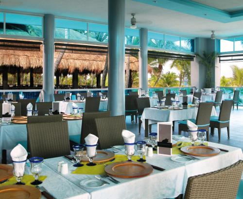 a dining room with tables and chairs and windows at Riu Yucatan - All Inclusive in Playa del Carmen