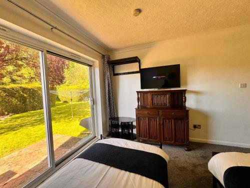 1 dormitorio con cama y ventana grande en High Trees Guest House Gatwick, en Hookwood