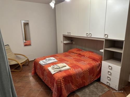 a bedroom with a bed and a chair and cabinets at casa Il Tiglio in Cretone