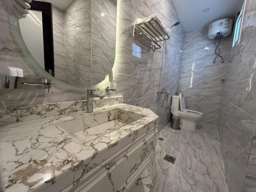 a white bathroom with a sink and a mirror at Elite House in Taif