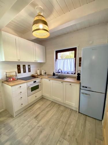una cucina con mobili bianchi e un frigorifero bianco di Jak Tu Ładnie - Osada i Siedlisko a Mikołajki