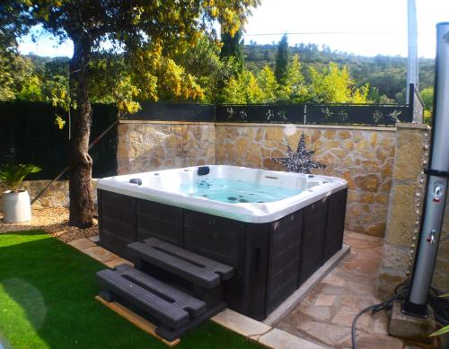 a hot tub in a yard with two black stools at La Rose des Vents & Spa - Gite Savane in Néoules