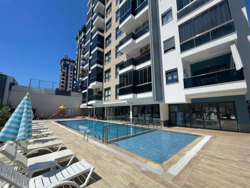 a swimming pool with lounge chairs and a building at SA Apartments! Mahmutlar, 300m to the Beach in Alanya