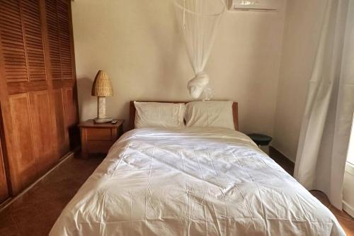 a white bed in a bedroom with a window at Carré Vert Guadeloupe Villa Privée Piscine in Gourbeyre