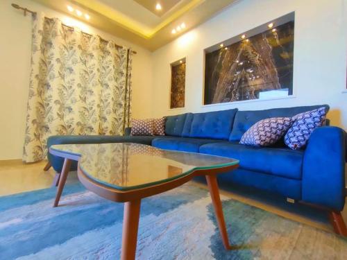 Join Inn Apartments في الإسكندرية: غرفة معيشة مع أريكة زرقاء وطاولة زجاجية