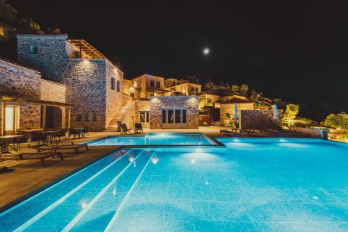 a swimming pool in front of a house at night at Sampatiki Suites - 4 Star Seaview Luxury Suites With Breakfast And Spa - Opened 2024 in Leonidio