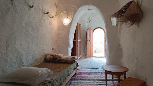 a hallway with a bed and a table in a room at Gite Douiret in Ad Duwayrāt