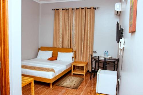 um pequeno quarto com uma cama e uma mesa em Mesuma Hotel Dodoma em Dodoma