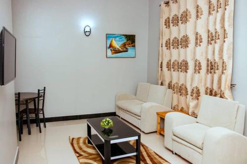 a living room with two white couches and a table at Mesuma Hotel Dodoma in Dodoma
