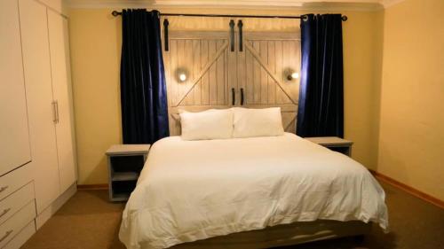 a bedroom with a large white bed with black curtains at Vimbainashe Villas 