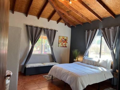 a bedroom with a bed and two windows at Stay with Class in the heart of wine country in San Antonio de las Minas