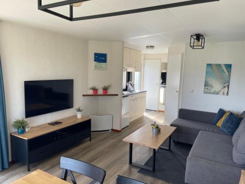 a living room with a couch and a flat screen tv at Blauwe Zeedistel in IJmuiden