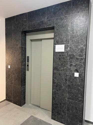 a bathroom with a door and a tile wall at Javorov list LUX in Šabac