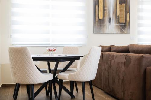 a dining room table with white chairs and a couch at Javorov list LUX in Šabac