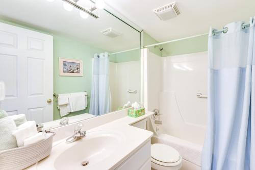 a bathroom with a sink and a toilet and a mirror at Emerald Dreams Lakefront PCB Vacation Rental! in Panama City Beach