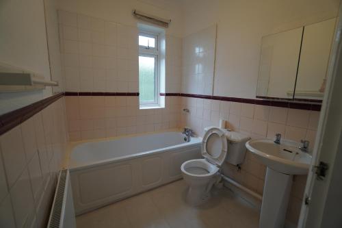 a bathroom with a tub and a toilet and a sink at Llewnodeb in Belvedere