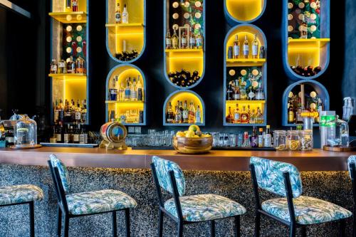 a bar with four chairs and a counter with liquor bottles at The First Collection Dubai Jumeirah Village Circle, a Tribute Portfolio Hotel in Dubai
