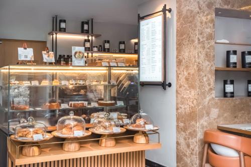 a display case in a bakery with pastries on plates at The First Collection Dubai Jumeirah Village Circle, a Tribute Portfolio Hotel in Dubai