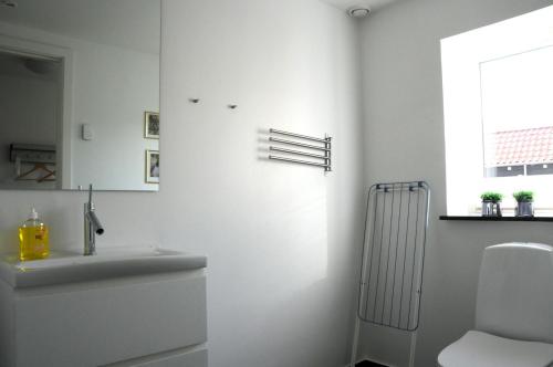 a white bathroom with a toilet and a sink at Skagen Apartment in Skagen