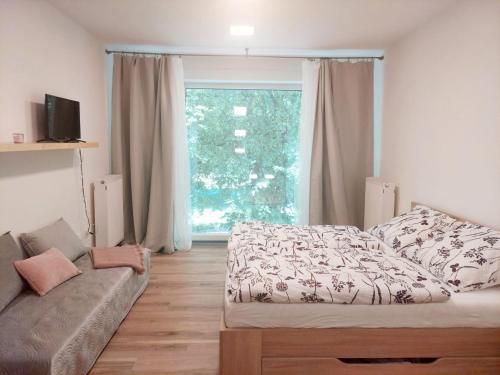 a bedroom with a bed and a couch and a window at Apartmán IRIS Poděbrady in Poděbrady
