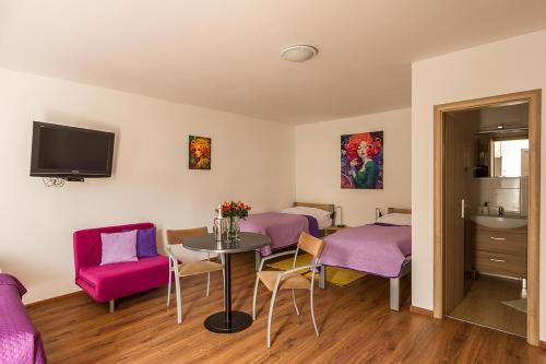 a room with two beds and a table with purple chairs at Apartmany Tereza & free parking in Bratislava