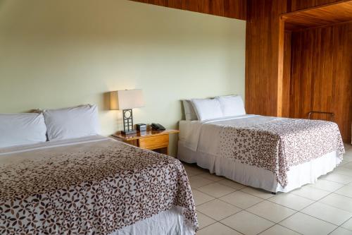a hotel room with two beds and a night stand at Hotel Ficus - Monteverde in Monteverde Costa Rica