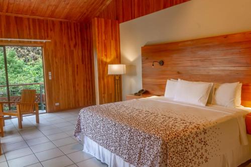 1 dormitorio con 1 cama grande y cabecero de madera en Hotel Ficus - Monteverde, en Monteverde