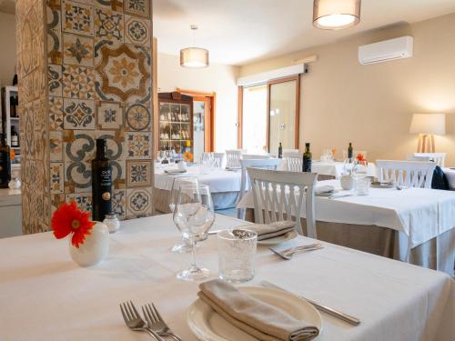 un comedor con mesas blancas y sillas blancas en Hotel Donatella, en Posada