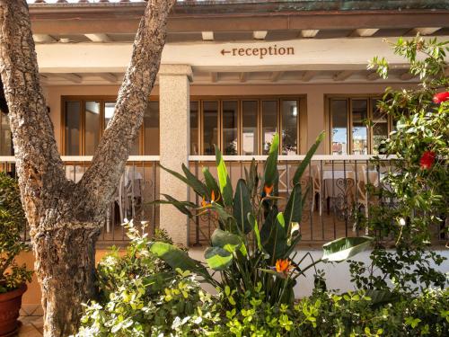a building with flowers and plants in front of it at Hotel Donatella in Posada
